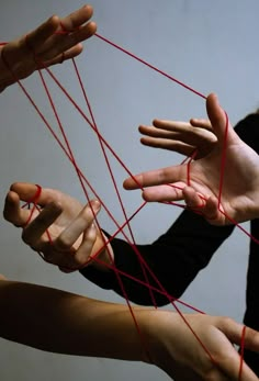 four hands are tangled together by red string