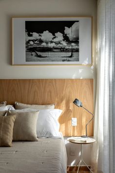 a bed with white sheets and pillows next to a painting on the wall above it