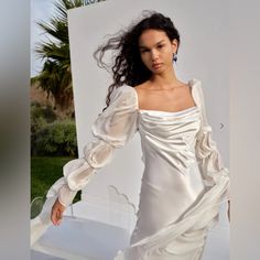 a woman in a white dress is posing for a photo with her hair blowing in the wind