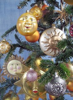 a christmas tree with ornaments hanging from it's branches and smiling faces on the top