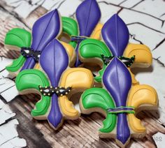 decorated cookies with purple, green and yellow flowers on top of each other in the shape of leaves