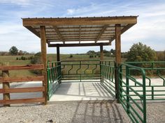 a green gated area with a wooden structure and metal railings on the side