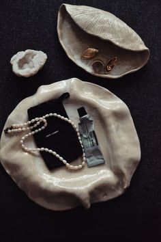 a white plate topped with pearls next to a pair of earrings and a black bag