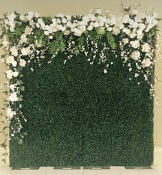 an artificial green wall with white flowers and greenery