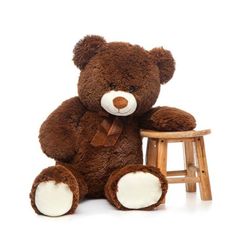 a brown teddy bear sitting next to a wooden stool