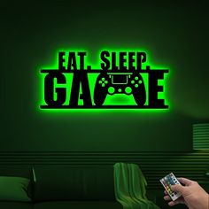 a person holding a game controller in front of a neon sign that reads eat sleep game