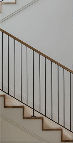 a cat sitting on top of a wooden stair case next to a bannister