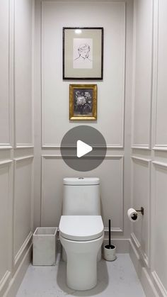 a white toilet sitting in a bathroom next to a framed photo on the wall and an empty roll of toilet paper