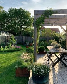 an outdoor dining area with wooden decking and potted plants on the side of it