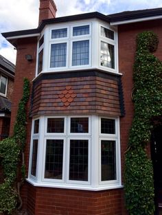 a red brick house with white windows and ivy growing on the side