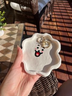 a person holding up a plate with two rings on it in front of a table