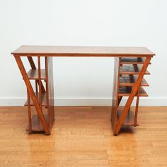 a wooden desk sitting on top of a hard wood floor next to a white wall