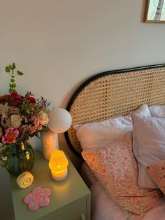 a bed with flowers and candles on it next to a night stand in front of a window