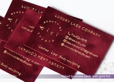 four red business cards with gold foil on them sitting next to each other in front of a white background