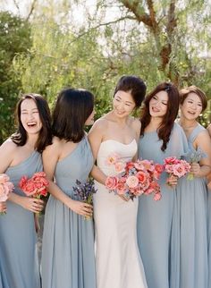 a group of women standing next to each other holding bouquets in their hands and laughing