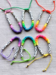 six bracelets with different colors and designs on the strings, all lined up together