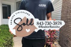 a man standing in front of a house holding up a sign that says sell realtor ranisha