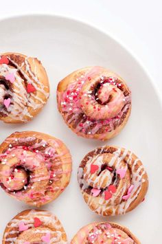 six donuts on a plate with sprinkles and icing are arranged in a circle