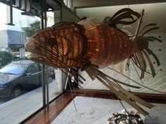 a fish made out of bamboo sitting in front of a window next to a car