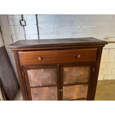 an old wooden cabinet with glass doors in the center and brown wood trim on top