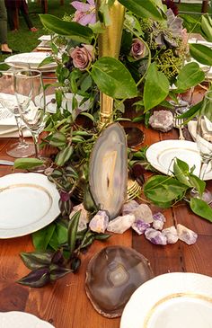 a wooden table topped with plates and flowers