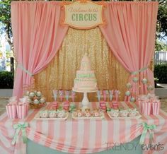 a pink and white table topped with lots of cupcakes next to a cake