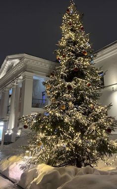 a lit christmas tree in front of a building