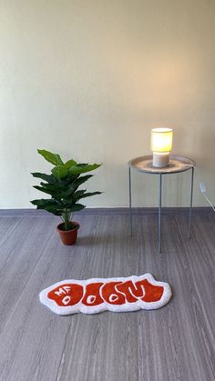 a cat rug on the floor next to a potted plant with a lit candle