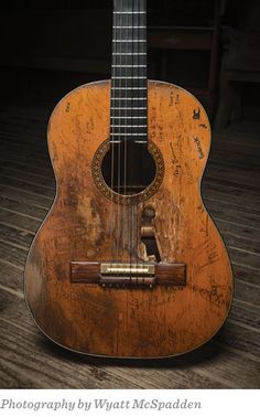 an old guitar sitting on top of a wooden floor