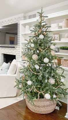 a small christmas tree in a wicker basket on the floor next to a fireplace