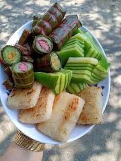 a person holding a plate with different types of food on it, including cucumbers and other vegetables