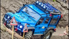 a blue truck driving down a dirt road next to another vehicle on top of a hill