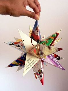 a hand is holding an origami star with pictures on it and the words merry christmas written below