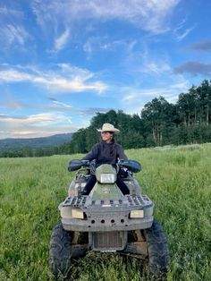 a man riding on the back of an atv in a grassy field under a blue sky