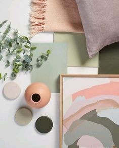 an arrangement of art, flowers and other items on a table with a pink pillow