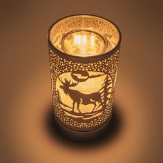 a lit candle that is sitting on a table with a deer design on it,