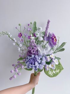 a hand holding a bouquet of flowers on a white background with the word love written in cursive writing