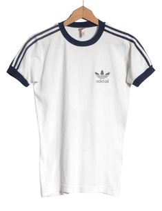 Vintage 1970's Adidas t shirt in a white colour. Trefoil on the chest and trademark three stripes down the sleeves. Made from a cotton polyester blend.  Condition: Excellent vintage condition. Bust: 34in Length: 25in More vintage clothing on our website www.brickvintage.com Affordable Trendy Adidas T-shirt, Vintage Adidas Shirt, Classic White Tops With Three Stripes, Classic White Top With Three Stripes, Retro Cotton T-shirt With Three Stripes, Retro White Top With Three Stripes, White Retro Top With Three Stripes, Retro Three Stripes T-shirt For Streetwear, Vintage White T-shirt With Screen Print