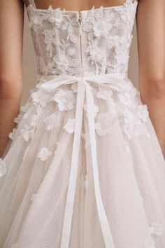 the back of a woman's wedding dress with white flowers and lace on it