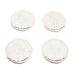 four white sand dollars with writing on them