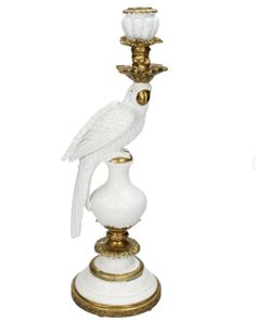 a white bird sitting on top of a gold and white candle holder with two candles