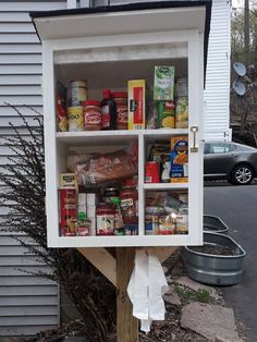 a cabinet filled with food sitting on top of a wooden pole next to a house