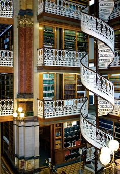 a spiral staircase in the middle of a library filled with books