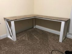 a corner desk in the corner of a room with carpet on the floor and a wall behind it