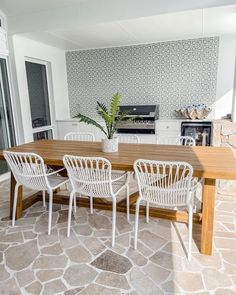 a table with chairs and a potted plant sitting on top of it next to an outdoor kitchen