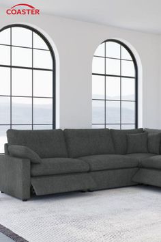 a large gray couch sitting in front of three windows