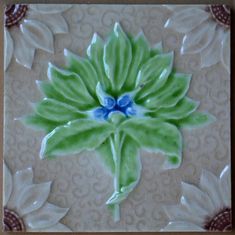 a green and blue flower with leaves on it's side is shown in the center of this tile