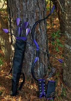 a bow and arrow stuck in the ground next to a tree with purple arrows sticking out of it