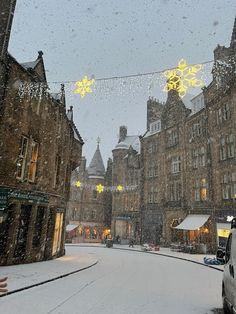 a snowy street with cars parked on the side and buildings in the backgroud