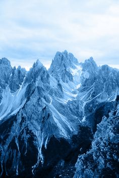 the mountains are covered in snow and blue hued clouds, with no one visible on them